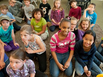 Classroom children sitting on floor listening to teacher